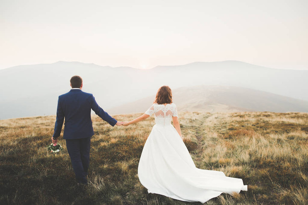 Beautiful wedding couple posing on top of a mountain at sunset - 写真・画像
