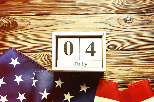 Retro style American flag and wooden cube calendar with 4th of July, USA Independence Day anniversary. Greeting card template, copy space on wood texture background. Top view, close up, vintage filter - Fotó, kép