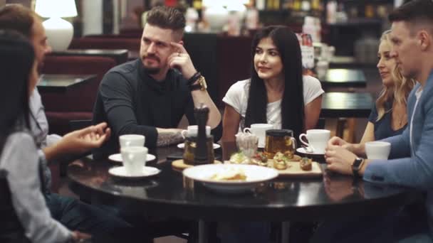 amigos se ríen y se divierten sentados en una mesa en un restaurante. Una compañía de amigos pasa tiempo juntos y disfruta socializando
. - Imágenes, Vídeo
