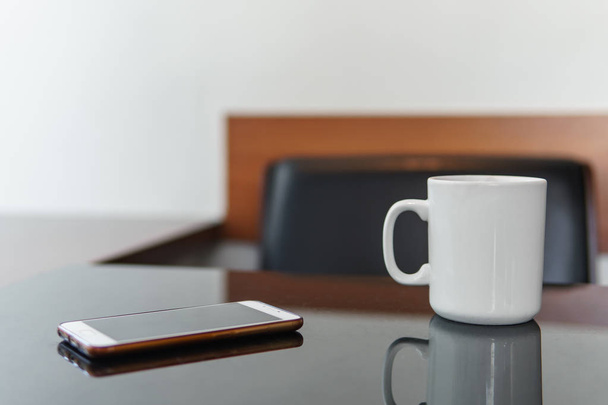 スマート フォンと白カフェでテーブルの上のコーヒー カップ. - 写真・画像