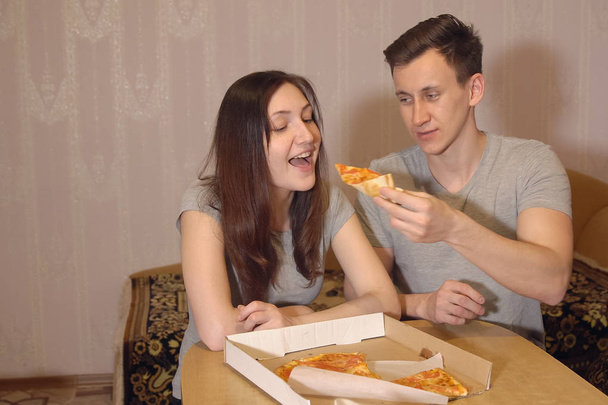 Beautiful woman and man eating pizza at home. - Photo, Image