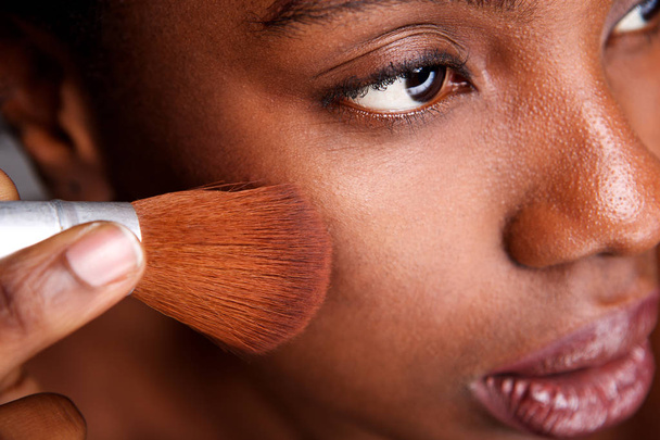 Close up side portrait of beautiful woman applying makeup with brush for smooth matte finish - Photo, Image