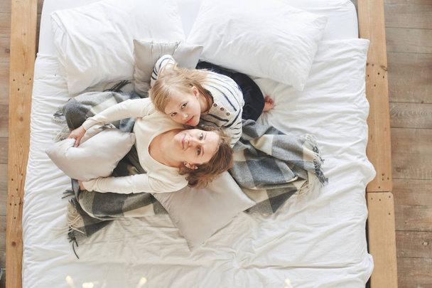 ママと娘が楽しみながら自宅のベッドの上に座って  - 写真・画像