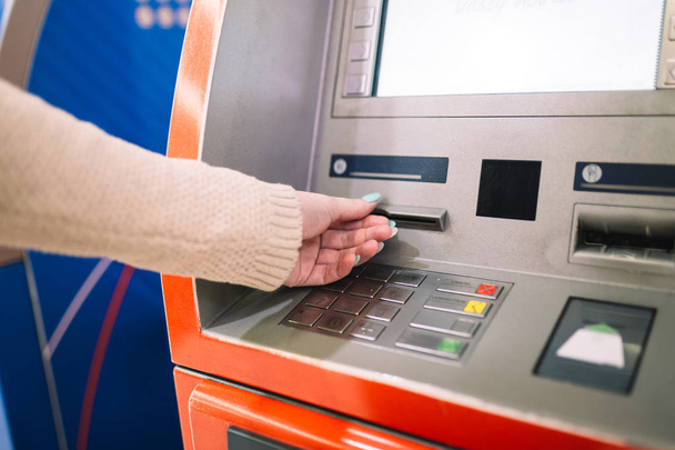 Молодая женщина снимает деньги с кредитной карты в банкомате. Селективный фокус
. - Фото, изображение