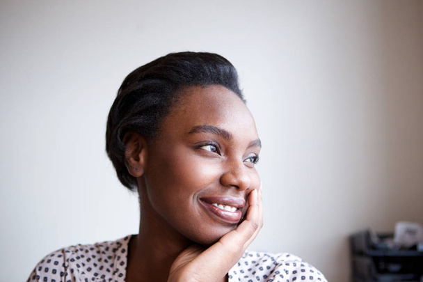 Retrato de cerca de una mujer afroamericana sonriente apoyada con la cabeza en la mano
  - Foto, imagen