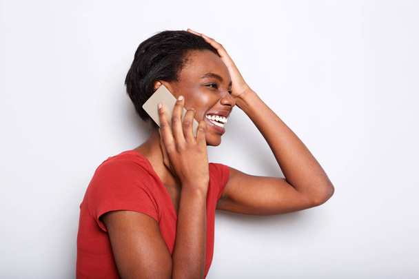 Close up side portrait of happy black woman talking on mobile phone and laughing - Φωτογραφία, εικόνα