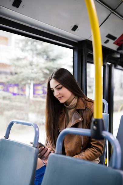 Beautiful young woman sitting in city bus with  mobile phone.  - Zdjęcie, obraz