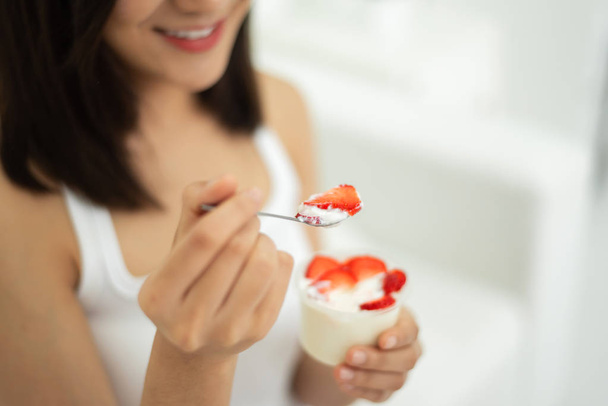 Young Asian Beautiful woman eating strawberries with yogurt on white background at home. Smiling Face. - Foto, afbeelding