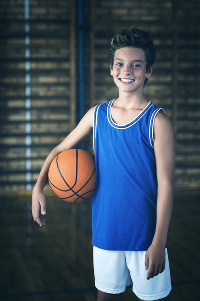 Портрет усміхненого хлопчика середньої школи, який тримає баскетбол у дворі
 - Фото, зображення