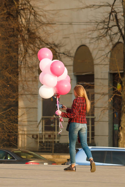 Dívka s barevnými balónky na ulici, pohled zezadu. Ta holka dělá selfie - Fotografie, Obrázek