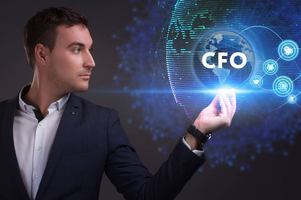 Business, Technology, Internet and network concept. Young businessman working on a virtual screen of the future and sees the inscription: CFO - Фото, изображение