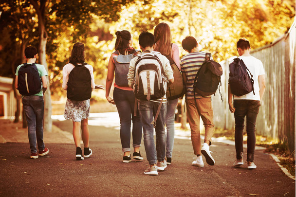 Rear view of school kids walking on road in campus at school - Fotó, kép