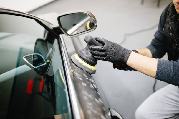 Car detailing - Worker with orbital polisher in auto repair shop.  - Fotografie, Obrázek