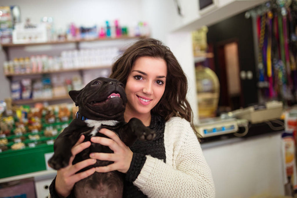 brunette woman with her French bulldog puppy in pet shop.  - Valokuva, kuva