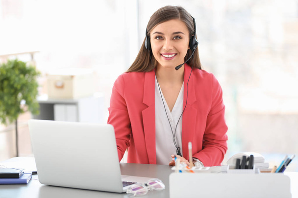 Young woman talking on phone through headset at workplace - Foto, imagen