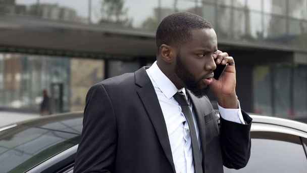 Confused businessman listening to threats from business competitor, phone call - 写真・画像