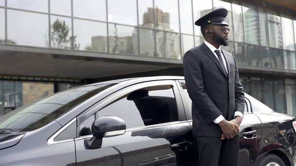 Driver of vip hotel service waiting for passengers near his car, ready to go - Foto, imagen