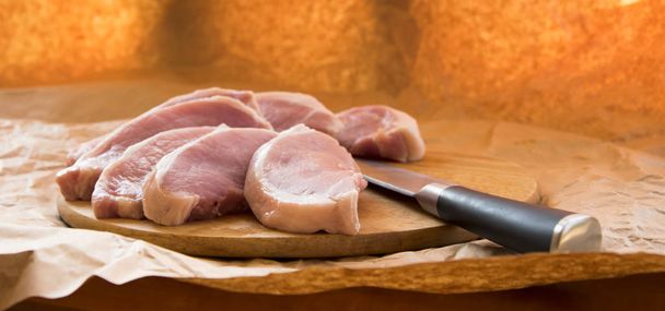 Свіжі сирі свинячі відбивні на обробній дошці. Аранжування на обгортковому папері
 - Фото, зображення