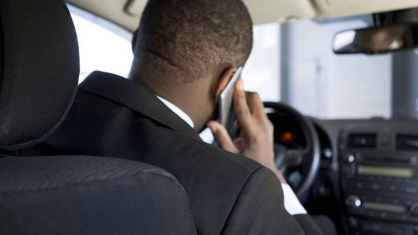 Uomo afro-americano che chiama al telefono dall'auto, stressante giornata di uomo d'affari
 - Foto, immagini