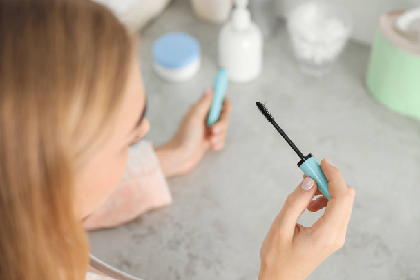 Young woman holding mascara brush with fallen eyelashes indoors - Foto, Imagem