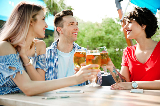 Young people with glasses of cold beer at table - Фото, изображение