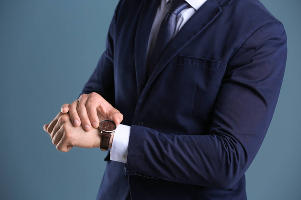 Businessman with wristwatch on color background. Time concept - Foto, afbeelding