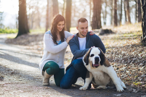 Young couple enjoying together in nature with their Saint Bernard puppy. - Φωτογραφία, εικόνα