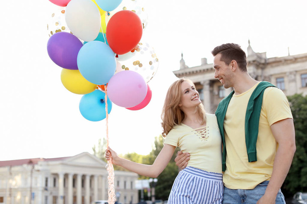 Young couple with colorful balloons outdoors on sunny day - Fotoğraf, Görsel