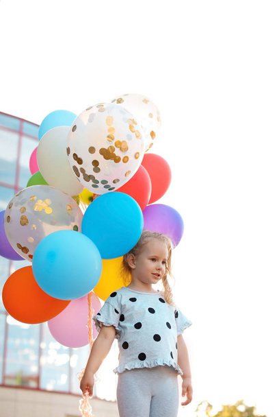 Cute little girl with colorful balloons outdoors on sunny day - Fotografie, Obrázek