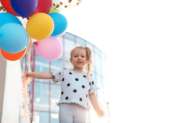 Cute little girl with colorful balloons outdoors on sunny day - Valokuva, kuva