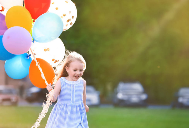 Little girl with colorful balloons outdoors on sunny day - Фото, зображення