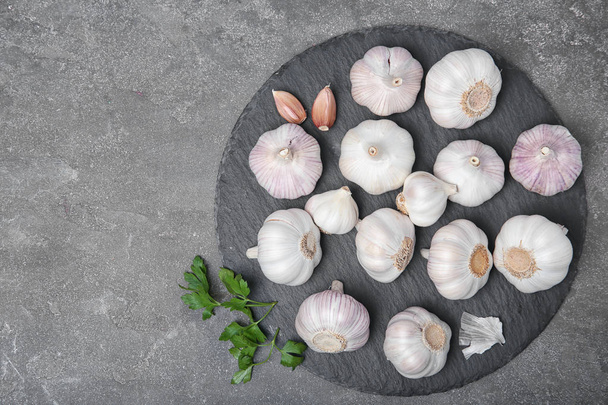 Slate plate with fresh garlic on gray background, top view - Photo, image