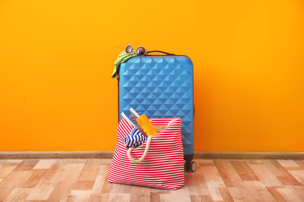 Suitcase and bag packed for summer journey on floor near color wall - Fotografie, Obrázek