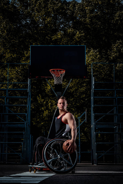 Πορτρέτο του έναν παίκτη μπάσκετ με αναπηρία σε μια αναπηρική καρέκλα σε ένα έδαφος ανοιχτό τυχερών παιχνιδιών. - Φωτογραφία, εικόνα