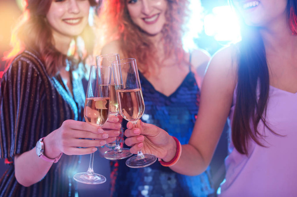 Jonge vrouwen chinking glazen in nachtclub, close-up. Verjaardagsfeest - Foto, afbeelding
