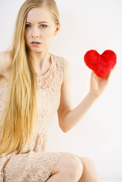 Sad lonely woman being alone holding red heart shape. Female missing someone during valentines. - Foto, imagen