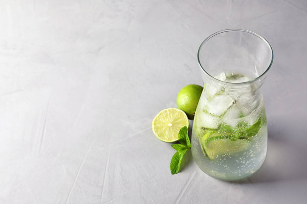 Natural lemonade with lime in jug on grey background - Foto, afbeelding