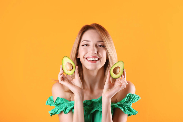 Portrait of young beautiful woman with ripe delicious avocado on color background - Foto, afbeelding