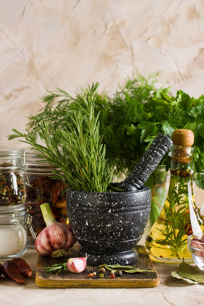 Marble mortar and pestles with rosemary on wooden cutting board jars with salt and pepper olive oil garlic herbs on beige background. Cooking food with spices, meal preparation. - Photo, Image