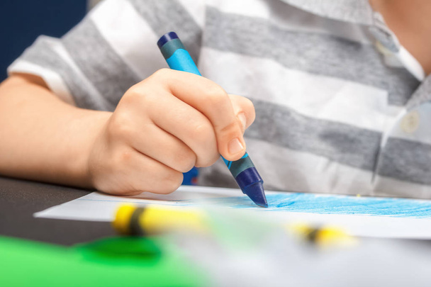 Beyaz bir kağıda balmumu renkli kalemler ile çizim. Çocuk yaratıcılık ve Hobiler kavramı. Çocuk kalem mavi beyaz kağıt üzerine çizer. Bebek eller yukarı - Fotoğraf, Görsel