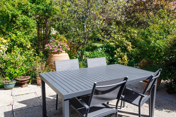 Цветущая терраса с серой садовой мебелью в саду весной
 - Фото, изображение