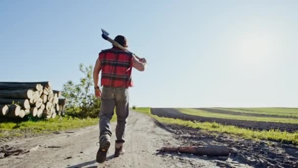 Casual man with axe walking on rural road - Video