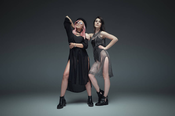 Дві модні дівчата в чорному модному вбранні позують
 - Фото, зображення