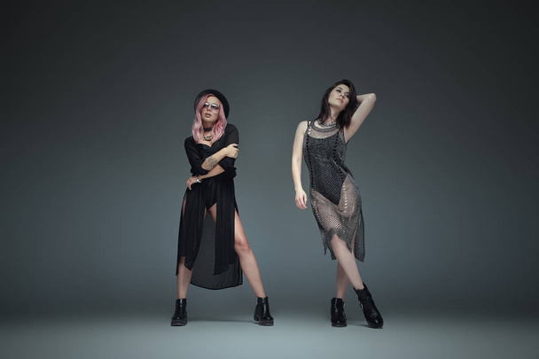 Kaksi muodikasta tyttöä yllään musta trendikäs asuja poseeraa
 - Valokuva, kuva