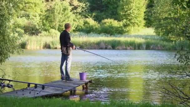 Een jongeman is vissen in een vijver - Video
