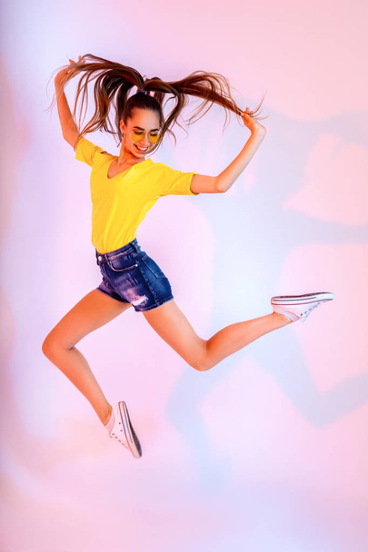 Success, dream, femenine girlish life concept. Excited brunette lady model is jumping up, wearing casual clothes, white shoes - 写真・画像
