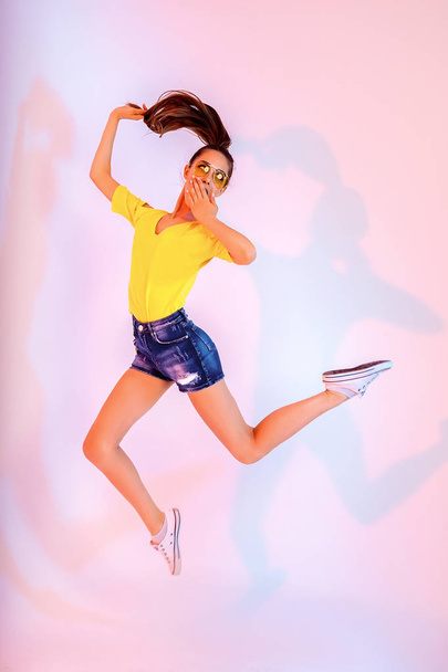 Success, dream, femenine girlish life concept. Excited brunette lady model is jumping up, wearing casual clothes, white shoes - 写真・画像