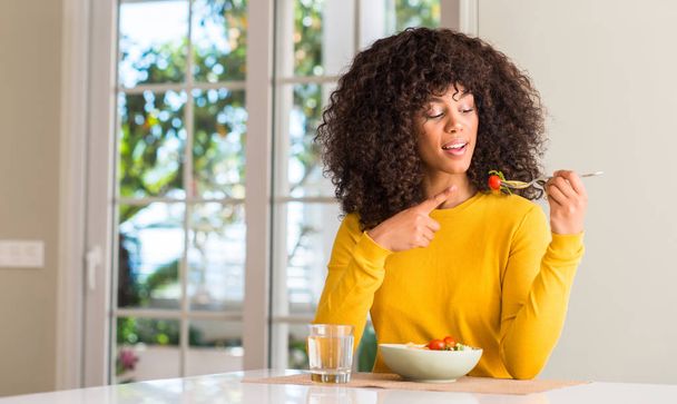 Afrikai-amerikai nő evés nagyon boldog, rámutatva a kéz és az ujjak tésztasaláta - Fotó, kép