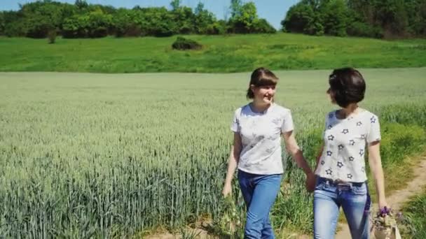 Δύο κορίτσια, κρατώντας τα χέρια περπάτημα στη φύση - Πλάνα, βίντεο