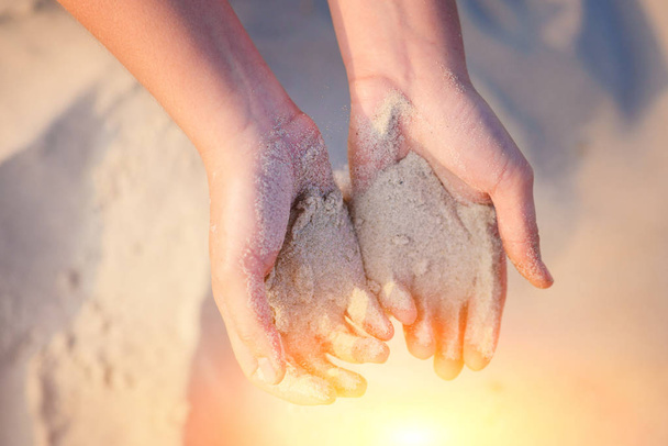 manos femeninas vierten arena en el suelo
. - Foto, imagen